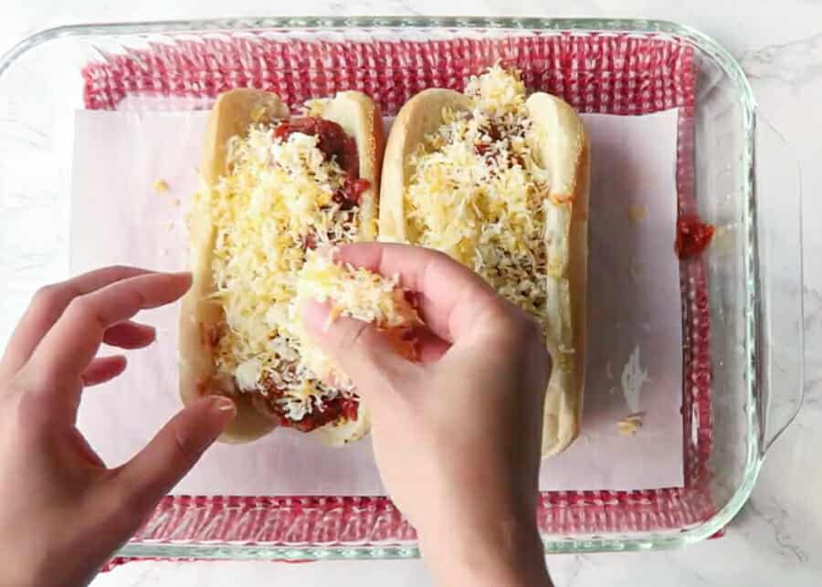 adding cheese to a meatball sub made with the best baked meatballs