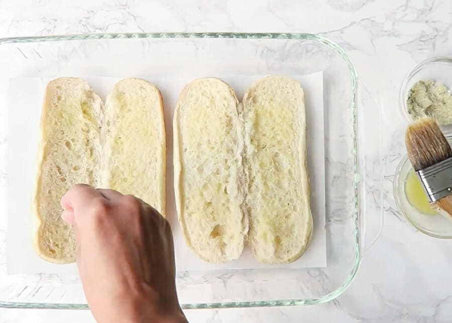 sprinkling garlic salt onto bread for meatball subs