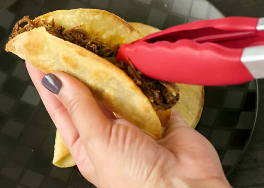 stuffing the baked crunchy taco shell with mexican shredded beef for the Crispy Shredded Beef Tacos 