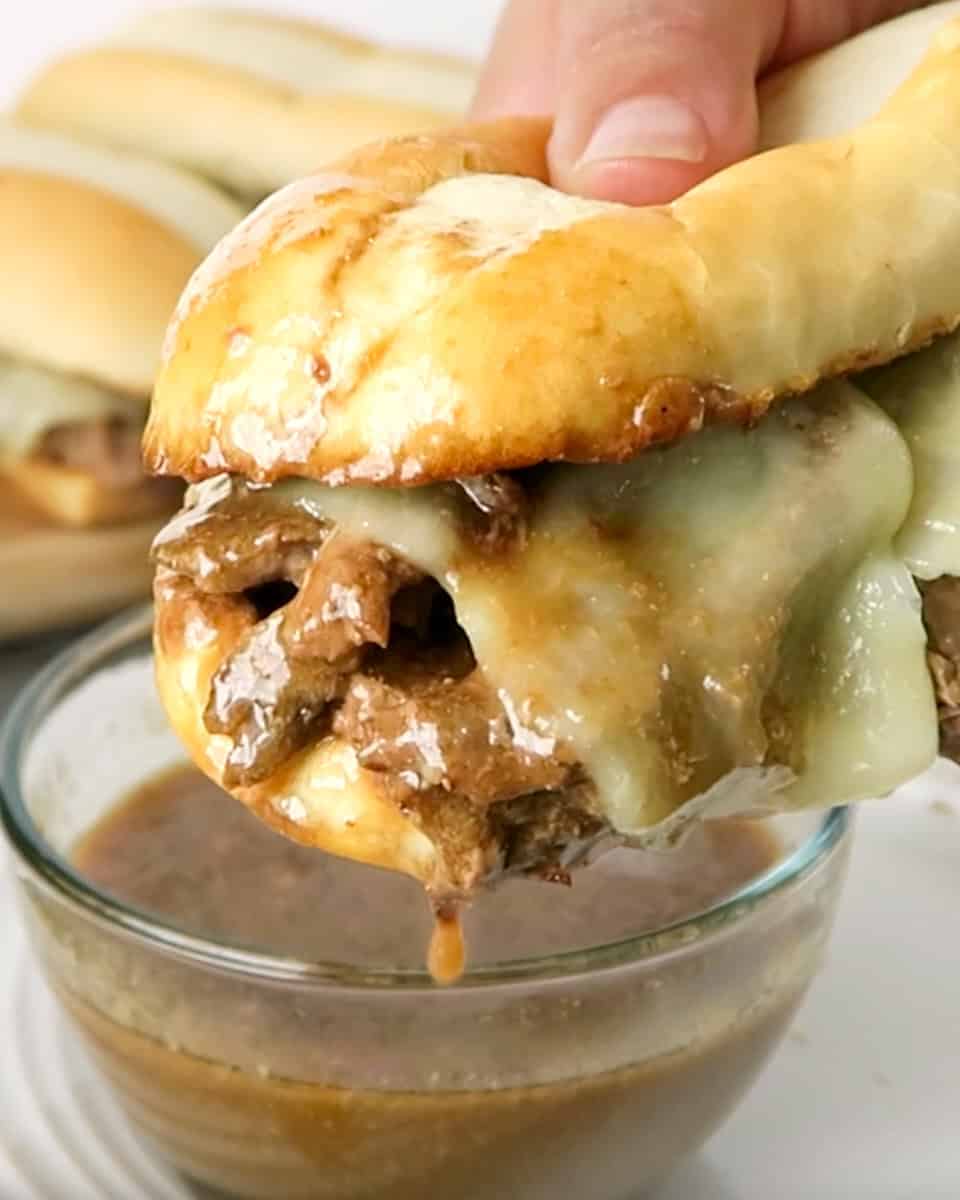 Bite shot of Easy French Dip Sandwiches dipped in au jus