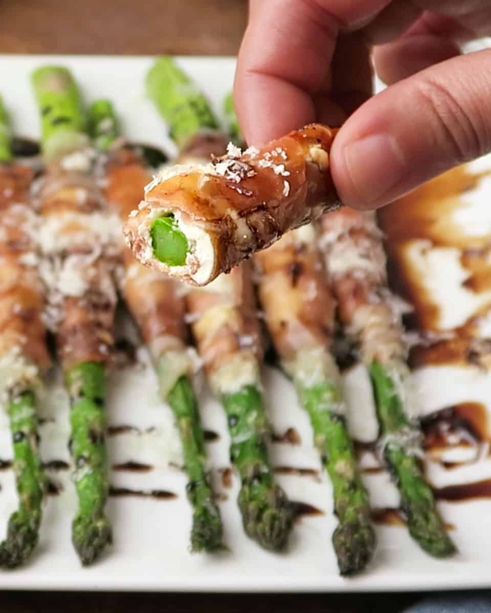 bite shot of Prosciutto Wrapped Asparagus with Cream Cheese topped with parmesan and balsamic glaze
